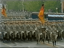 a group of soldiers marching down a street with flags