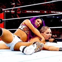 two women are wrestling in a ring and one of them is wearing purple hair .