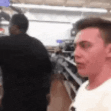 a man in a white shirt is standing in a store with a man in a black jacket behind him .