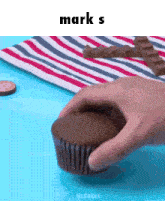 a person is holding a chocolate cupcake with the word mark s on the bottom