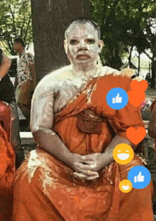 a man with white paint on his face is sitting in front of a tree with thumbs up and hearts around him