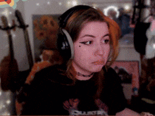 a girl wearing headphones is sitting in front of a microphone and a guitar