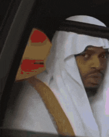 a man in a white robe is sitting in a car and looking out the window
