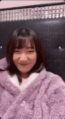 a woman in a purple robe is smiling while sitting on a chair