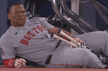 a boston baseball player laying on the ground with his bats