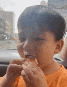 a young boy is eating a hamburger in a car .