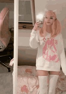 a girl with pink hair is taking a picture of herself in a mirror