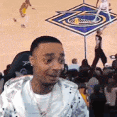 a man is sitting in front of a basketball court watching a basketball game .