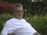 a man wearing a white shirt is sitting in a chair