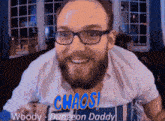 a man with glasses and a beard is smiling and says chaos