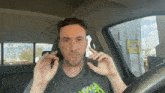 a man in a metallica shirt sits in the driver 's seat of a car