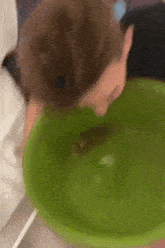 a person is drinking water from a green bowl