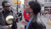 a man wearing a shirt that says hhhb talks to a woman