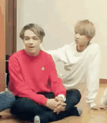 two young men are sitting on the floor with their legs crossed .