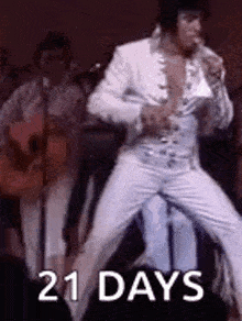 elvis presley is dancing on stage while holding a microphone and a guitar .