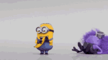 two minions , one yellow and one purple , are standing next to each other on a white surface .