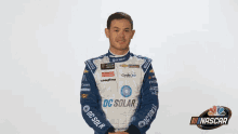 a man wearing a blue and white racing suit with dc solar written on the sleeves