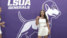 a woman in a white dress stands in front of a lsua generals logo