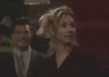 a man in a suit and tie stands next to a woman in a black top