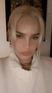 a woman with blonde hair wearing a white sweater
