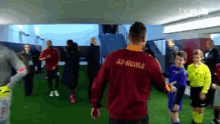 a man wearing a red roma shirt stands in a locker room