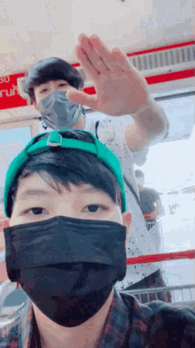 a man wearing a black mask and a green hat is standing next to another man wearing a mask