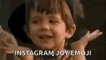 a little boy is smiling and making a funny face while holding his hands up .