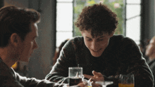 two young men are sitting at a table with a glass of orange juice in front of them