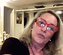 a woman wearing red glasses and earrings is looking at the camera