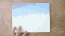 a person is holding a piece of paper with a painting on it