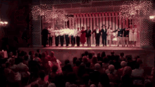 a group of people standing on a stage with a crowd watching