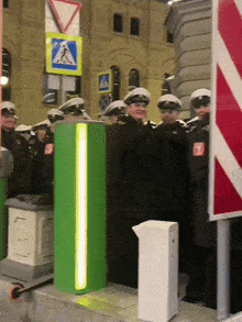 a group of police officers are standing next to a green pole