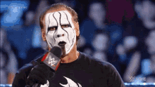 a man with a mask on his face is holding a microphone .
