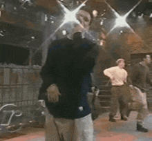a man in a black shirt is dancing in a room with other men .