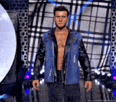 a man in a denim jacket and leather sleeves is standing in front of a checkered wall ..