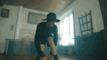 a man in a black hat is kneeling down in a dark room