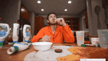 a man sitting at a table with a bowl of food and bottles of mayonnaise