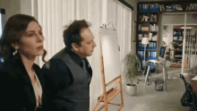 a man and a woman are standing in front of a white board