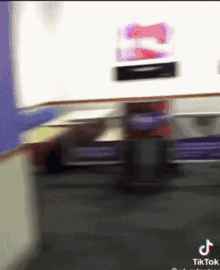a blurred image of a person standing next to a table with a tik tok logo on the bottom .