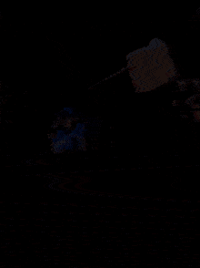 a man with blue hair is flying through the air in a dark room .