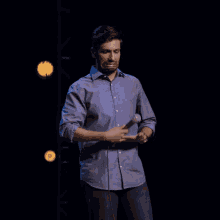 a man in a blue shirt is holding a microphone on a stage