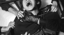 a black and white photo of a man with his mouth open being held by a group of people .