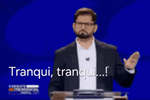a man in a suit and glasses is giving a speech at a podium and says tranquil , tranquil ...