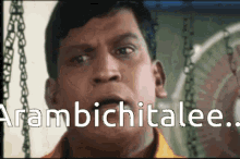 a man in a yellow shirt is making a funny face with the words " arambichitalee " written below him