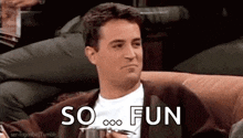 a man is sitting on a couch holding a cup and saying `` so fun '' while holding a cup of coffee .