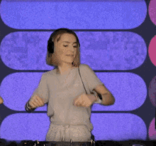 a woman wearing headphones is playing music on a turntable in front of a colorful background .