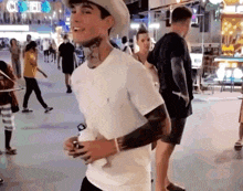 a man wearing a hat and a white t-shirt is walking down a street .