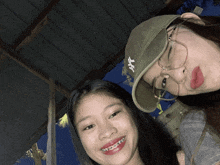 two girls are posing for a picture and one is wearing a hat with ny on it