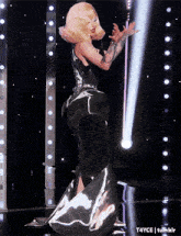 a woman in a long black dress is dancing on a stage with a tumblr logo in the corner