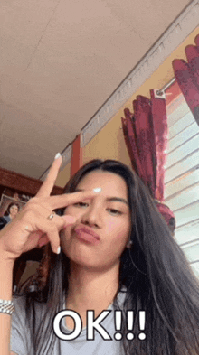 a woman with long hair is making a peace sign and says ok !!